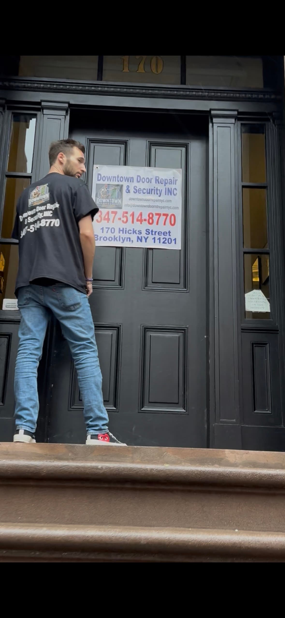 Downtown Door Repair & Security tech at the 170 Hicks St entrance — full business banner with phone and address on the door