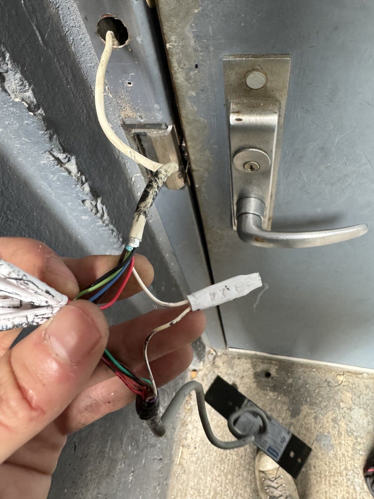 Intercom wiring exposed beside a gray building door during service